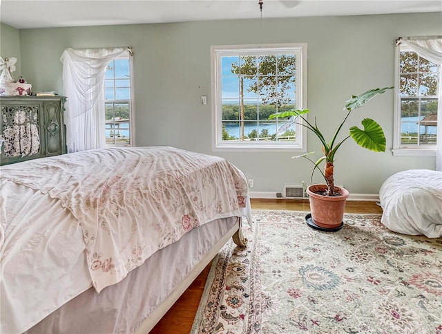 bedroom featuring hardwood / wood-style floors and a water view