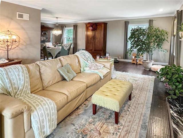 living room with hardwood / wood-style floors, a wealth of natural light, a notable chandelier, and ornamental molding