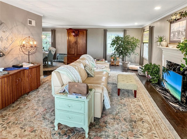 living room featuring ornamental molding, dark wood-type flooring, a healthy amount of sunlight, and a high end fireplace