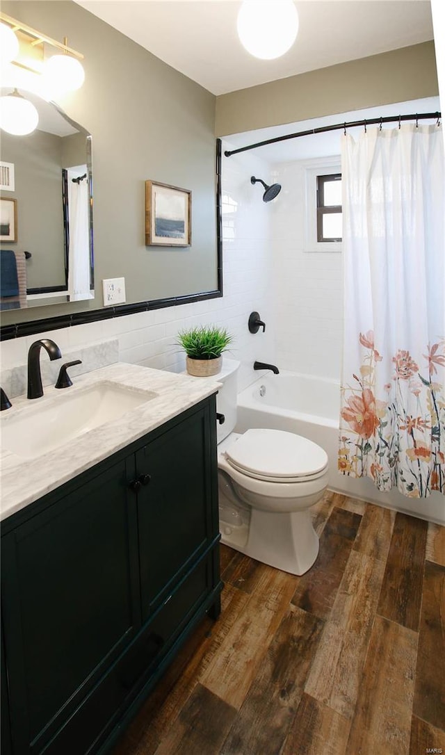 full bathroom with hardwood / wood-style floors, vanity, toilet, shower / bathtub combination with curtain, and tile walls