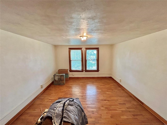 unfurnished room featuring light wood-type flooring and a textured ceiling