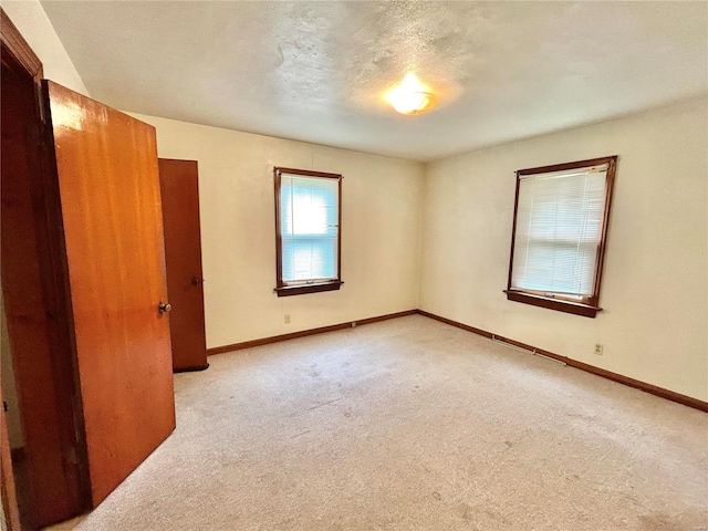 empty room with a textured ceiling and light colored carpet