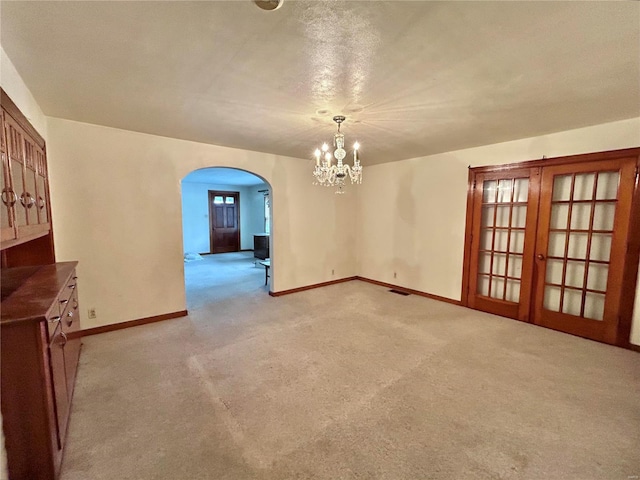 spare room featuring a textured ceiling, light carpet, and a chandelier