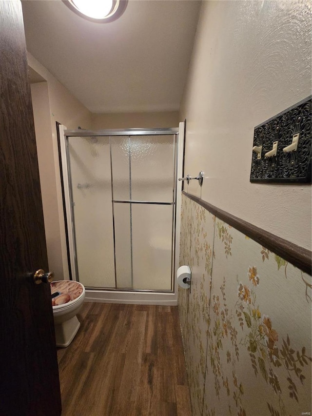 bathroom featuring hardwood / wood-style floors, a shower with shower door, and toilet