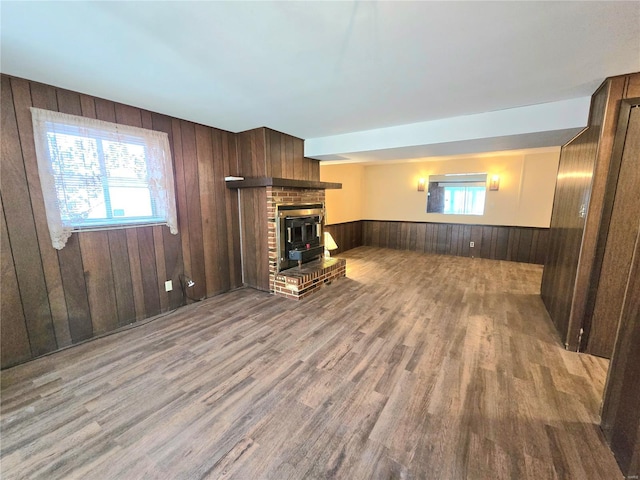 unfurnished living room with plenty of natural light, light hardwood / wood-style floors, and wooden walls