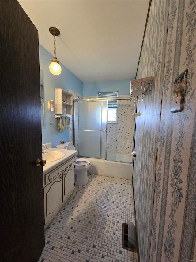 full bathroom featuring toilet, vanity, and shower / bath combination with glass door