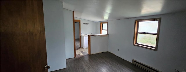 unfurnished room featuring baseboard heating, vaulted ceiling, and dark hardwood / wood-style flooring