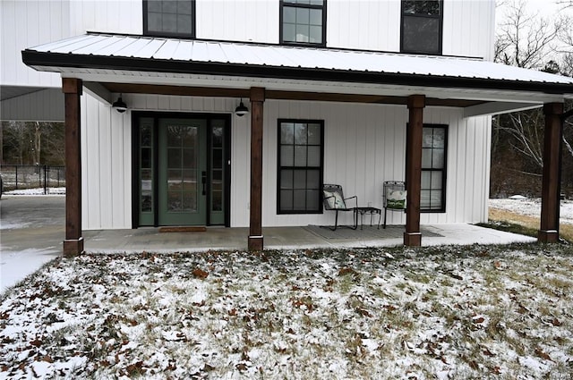 snow covered rear of property featuring covered porch