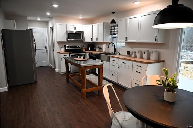 kitchen with sink, decorative light fixtures, appliances with stainless steel finishes, and white cabinetry