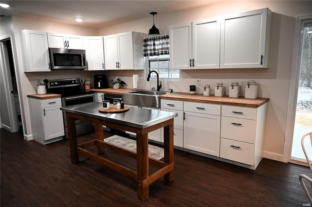 kitchen with decorative light fixtures, stainless steel appliances, and white cabinets