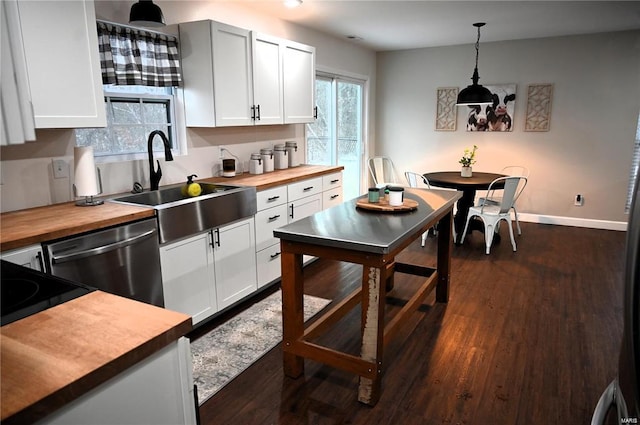 kitchen featuring hanging light fixtures, wooden counters, and white cabinets