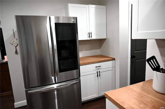 kitchen featuring dark wood-type flooring, stainless steel refrigerator, white cabinets, and butcher block countertops