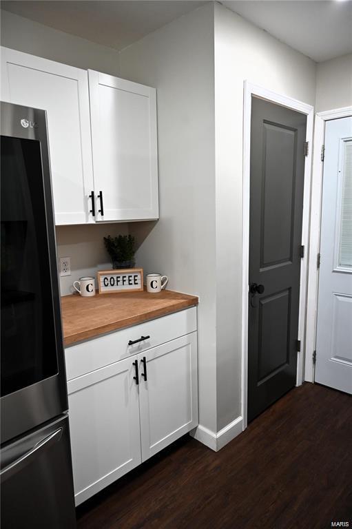 kitchen featuring white cabinetry, dark hardwood / wood-style flooring, butcher block counters, and stainless steel refrigerator