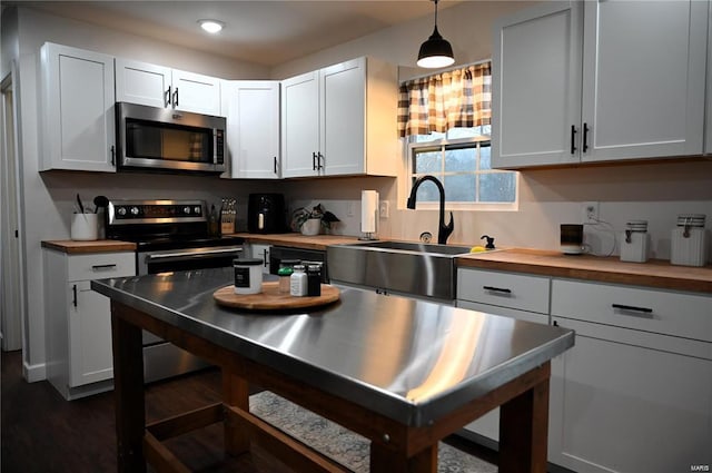 kitchen featuring sink, decorative light fixtures, stainless steel appliances, and white cabinets