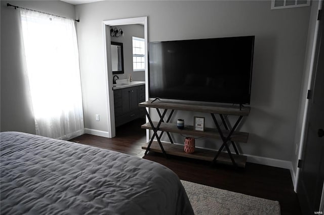 bedroom featuring sink, ensuite bathroom, and dark hardwood / wood-style flooring