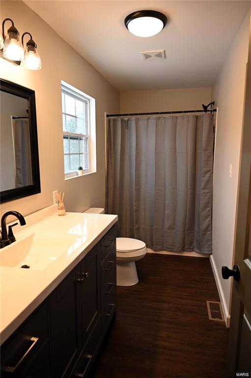 bathroom featuring walk in shower, vanity, toilet, and hardwood / wood-style floors