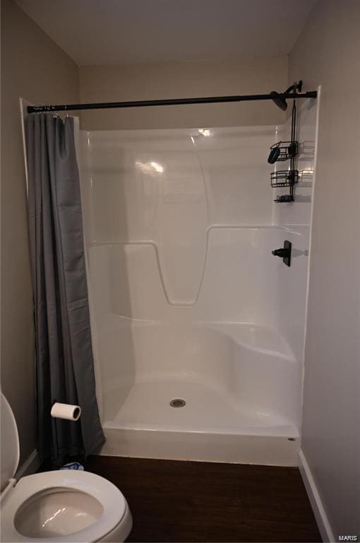 bathroom featuring hardwood / wood-style floors, a shower with curtain, and toilet