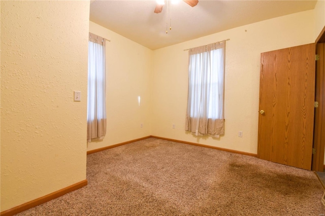 empty room featuring ceiling fan and carpet