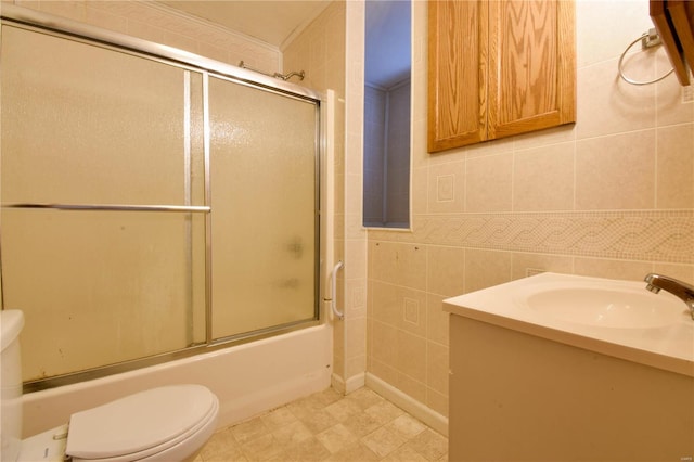 full bathroom featuring combined bath / shower with glass door, toilet, tile walls, and vanity