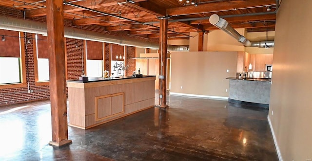 interior space with light brown cabinetry and brick wall