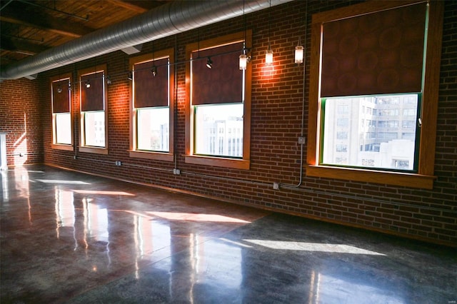 spare room with concrete flooring and brick wall