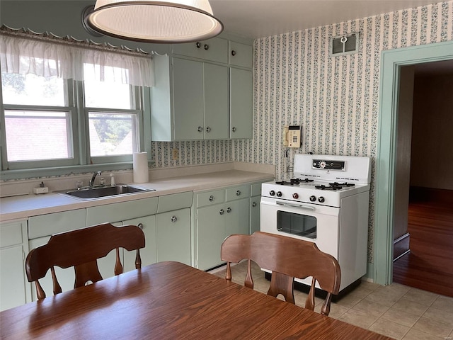 kitchen with light hardwood / wood-style floors, sink, green cabinets, and white gas range oven