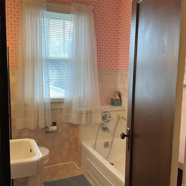 bathroom featuring tile walls, tile patterned flooring, toilet, and a bathing tub