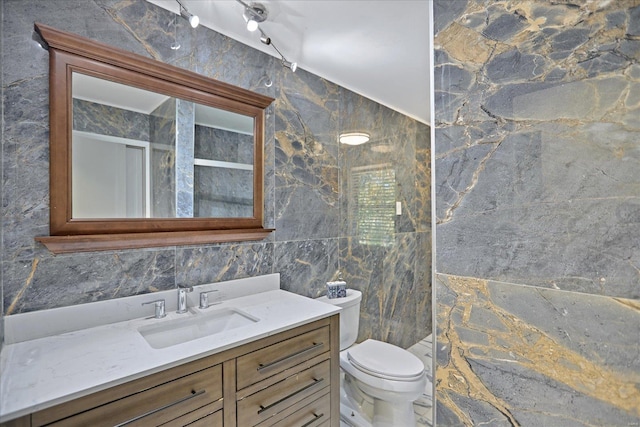 bathroom with vanity, tile walls, and toilet