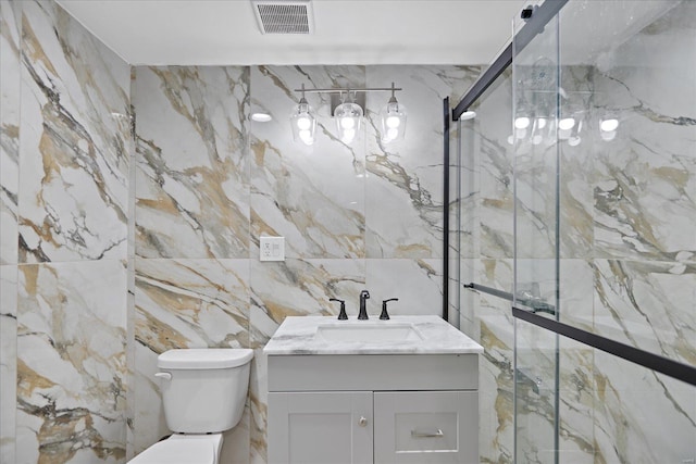 bathroom featuring tile walls, a shower with door, vanity, and toilet