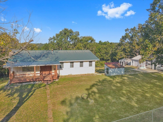 back of house with a deck, a yard, and an outbuilding