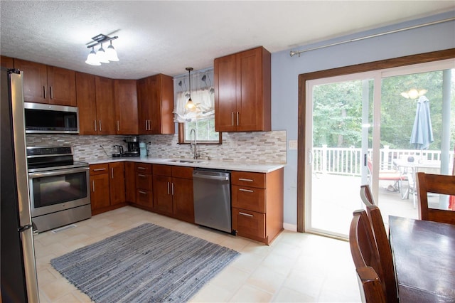 kitchen featuring sink, appliances with stainless steel finishes, decorative light fixtures, and plenty of natural light