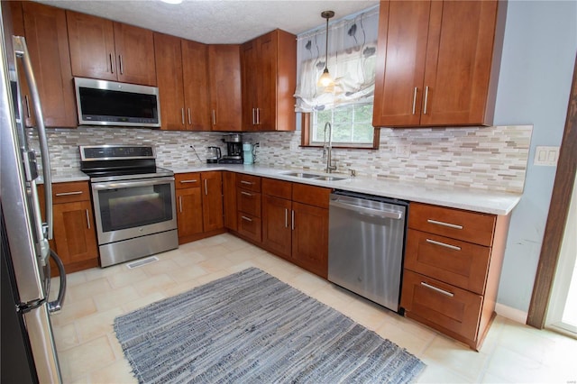 kitchen with sink, pendant lighting, appliances with stainless steel finishes, a textured ceiling, and tasteful backsplash