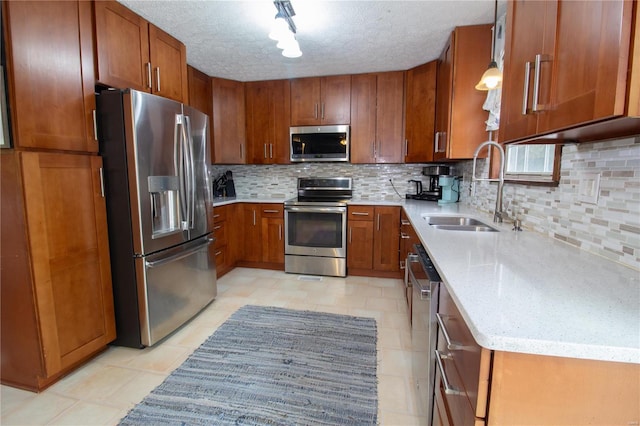 kitchen with light tile patterned floors, appliances with stainless steel finishes, backsplash, sink, and decorative light fixtures