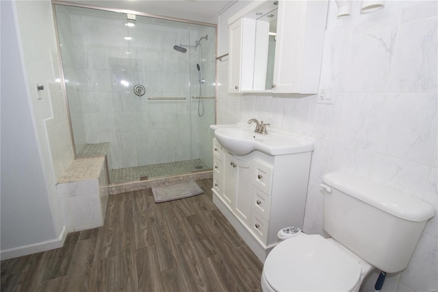 bathroom featuring tiled shower, toilet, vanity, hardwood / wood-style floors, and tile walls