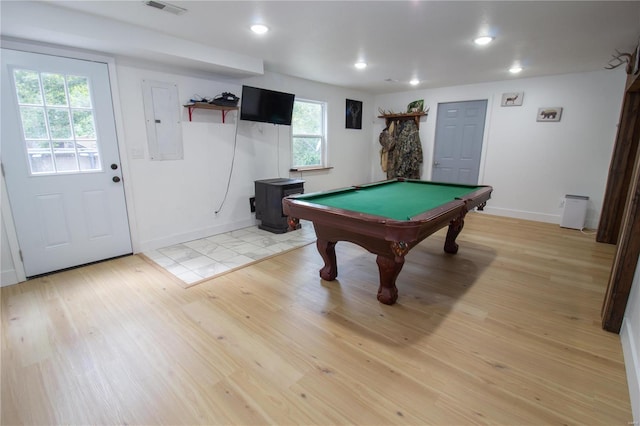 game room featuring light hardwood / wood-style floors, a wood stove, electric panel, and billiards