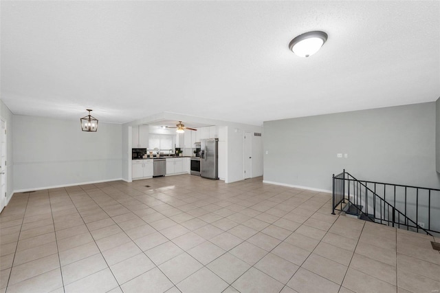 unfurnished living room featuring light tile patterned flooring and ceiling fan with notable chandelier