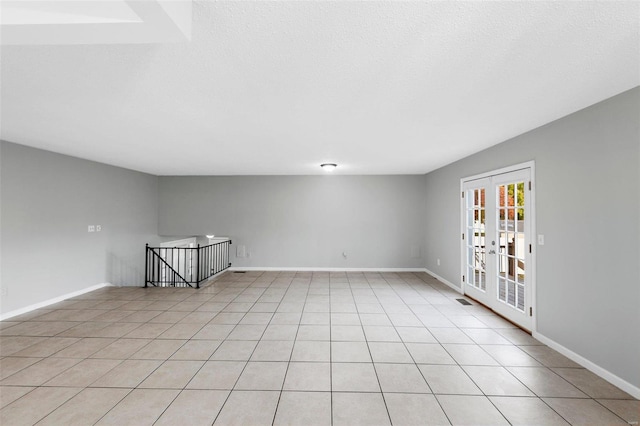 empty room featuring french doors and light tile patterned flooring