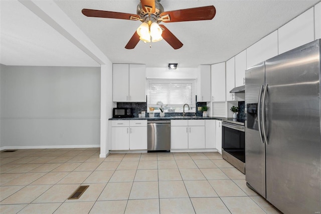 kitchen with stainless steel appliances, decorative backsplash, ventilation hood, and white cabinets