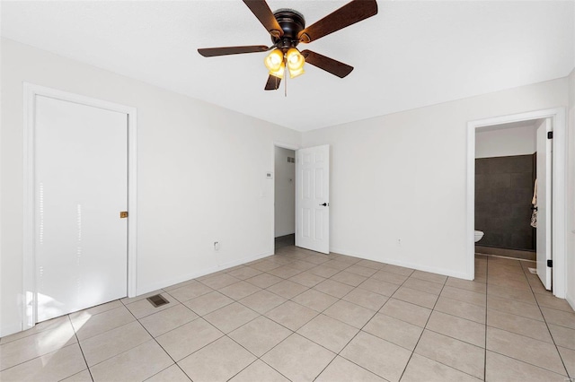 unfurnished bedroom with ensuite bath, light tile patterned floors, and ceiling fan