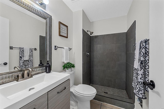 bathroom with vanity, a tile shower, toilet, and tile patterned flooring