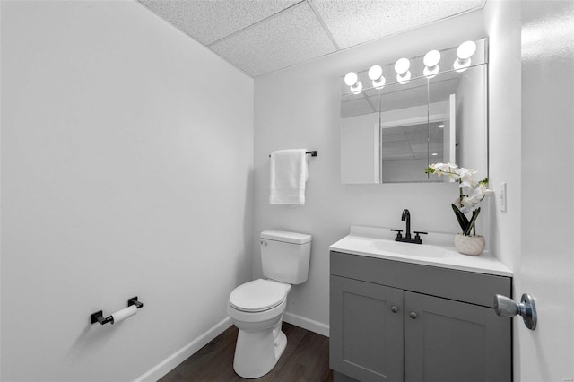 bathroom with vanity, wood-type flooring, toilet, and a paneled ceiling