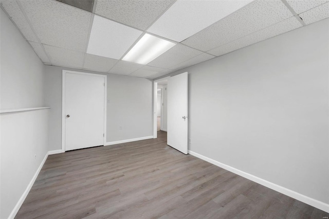 basement with wood-type flooring and a paneled ceiling