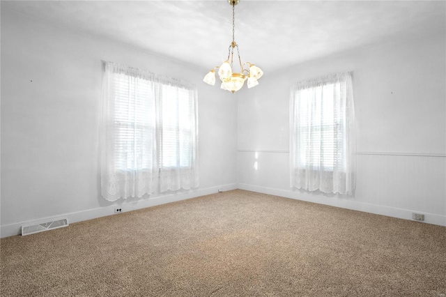 empty room with carpet flooring, plenty of natural light, and a notable chandelier