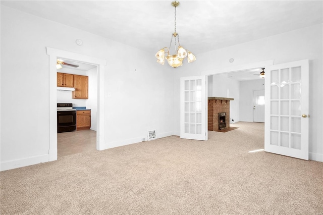 unfurnished living room with a fireplace, ceiling fan with notable chandelier, light colored carpet, and french doors