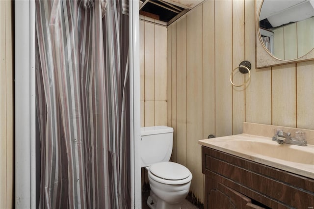 bathroom featuring vanity, toilet, and wood walls