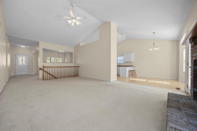 unfurnished living room featuring a fireplace, ceiling fan with notable chandelier, light colored carpet, and lofted ceiling