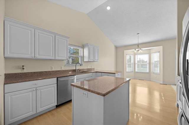 kitchen featuring a chandelier, stainless steel appliances, vaulted ceiling, and white cabinetry