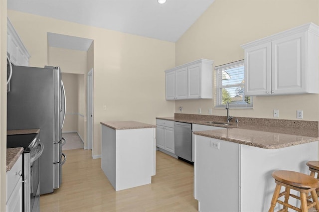 kitchen with a center island, sink, stainless steel appliances, white cabinets, and light wood-type flooring