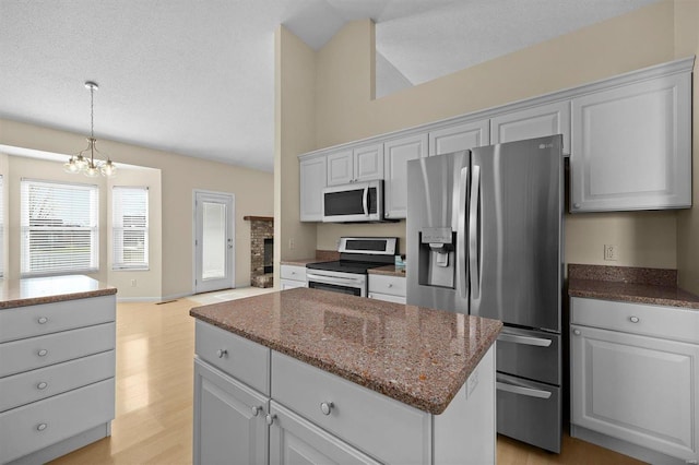 kitchen with a center island, an inviting chandelier, appliances with stainless steel finishes, light hardwood / wood-style floors, and white cabinetry