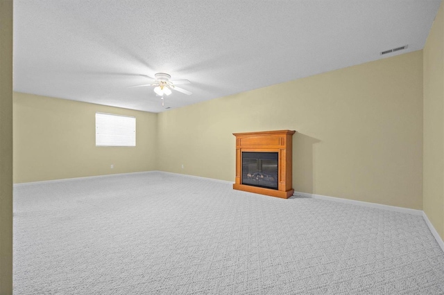 unfurnished living room with carpet flooring, ceiling fan, and a textured ceiling